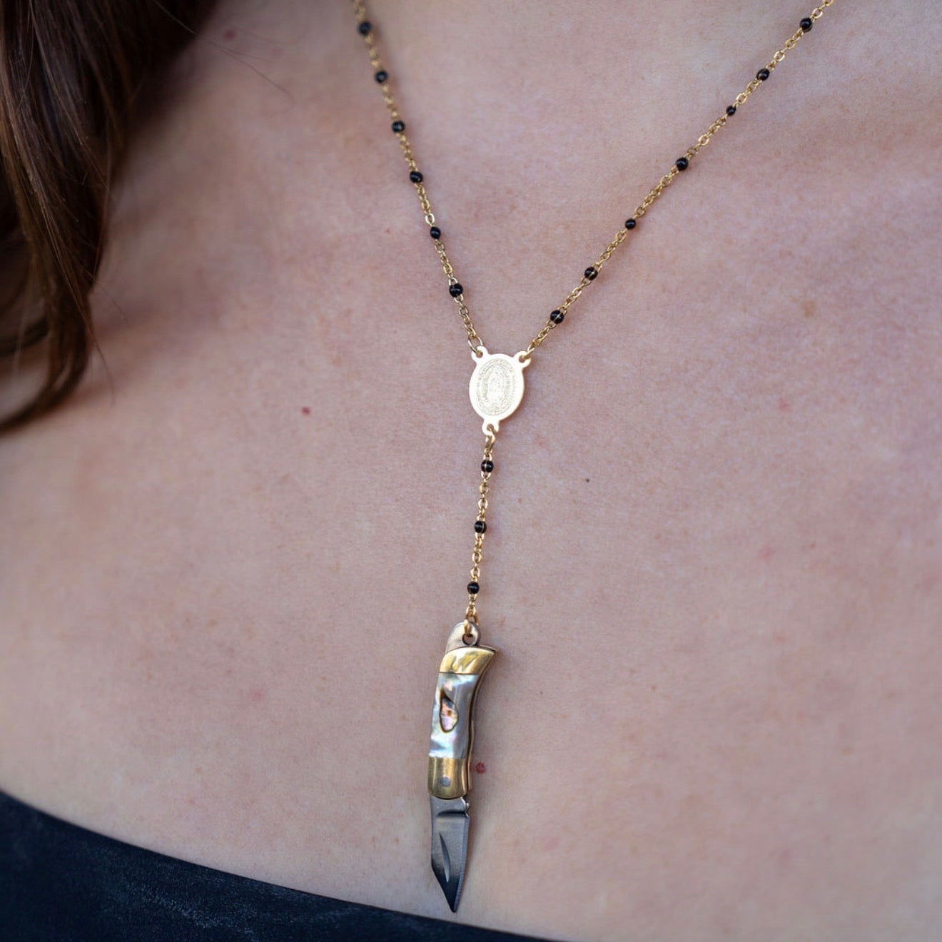 Necklace with a knife pendant on a person's neck