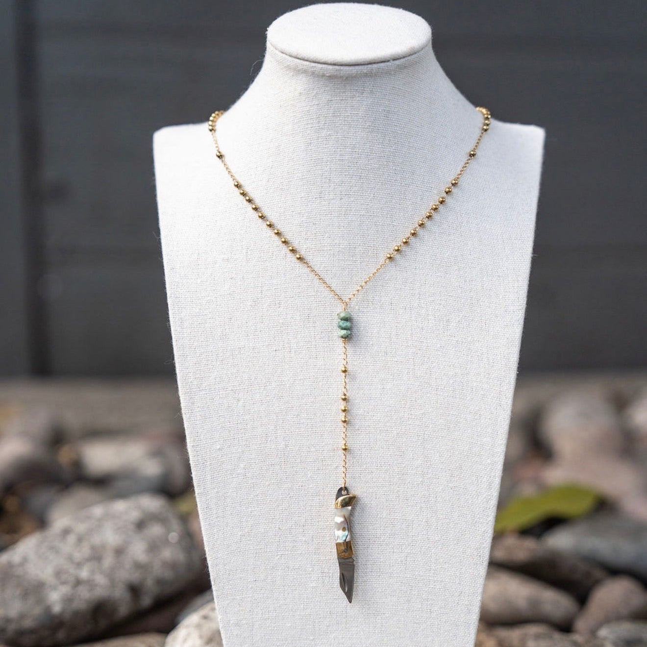Necklace with a pendant on a mannequin bust against a natural stone background