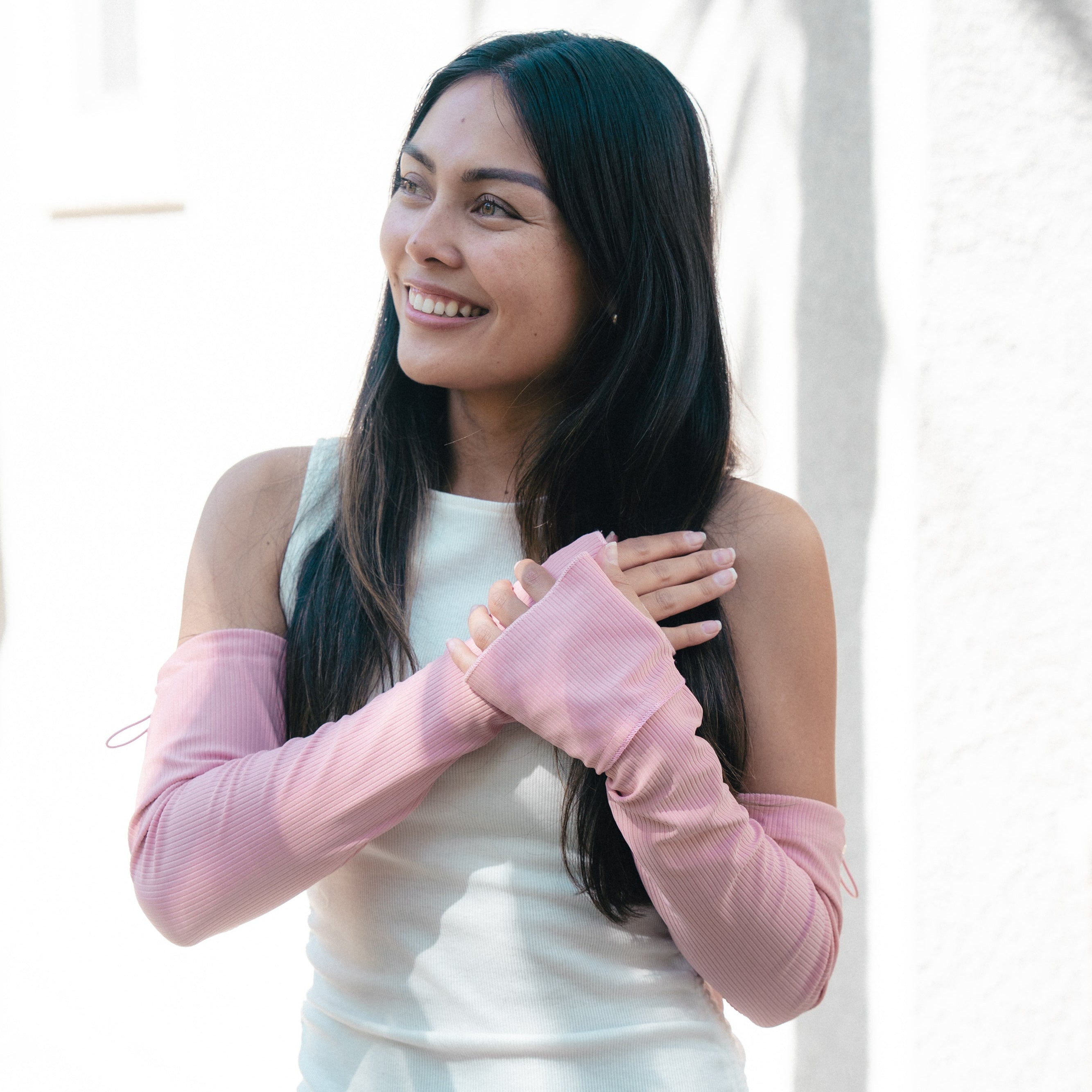 Woman wearing a light blue dress with pink long-sleeve gloves, standing against a white background.