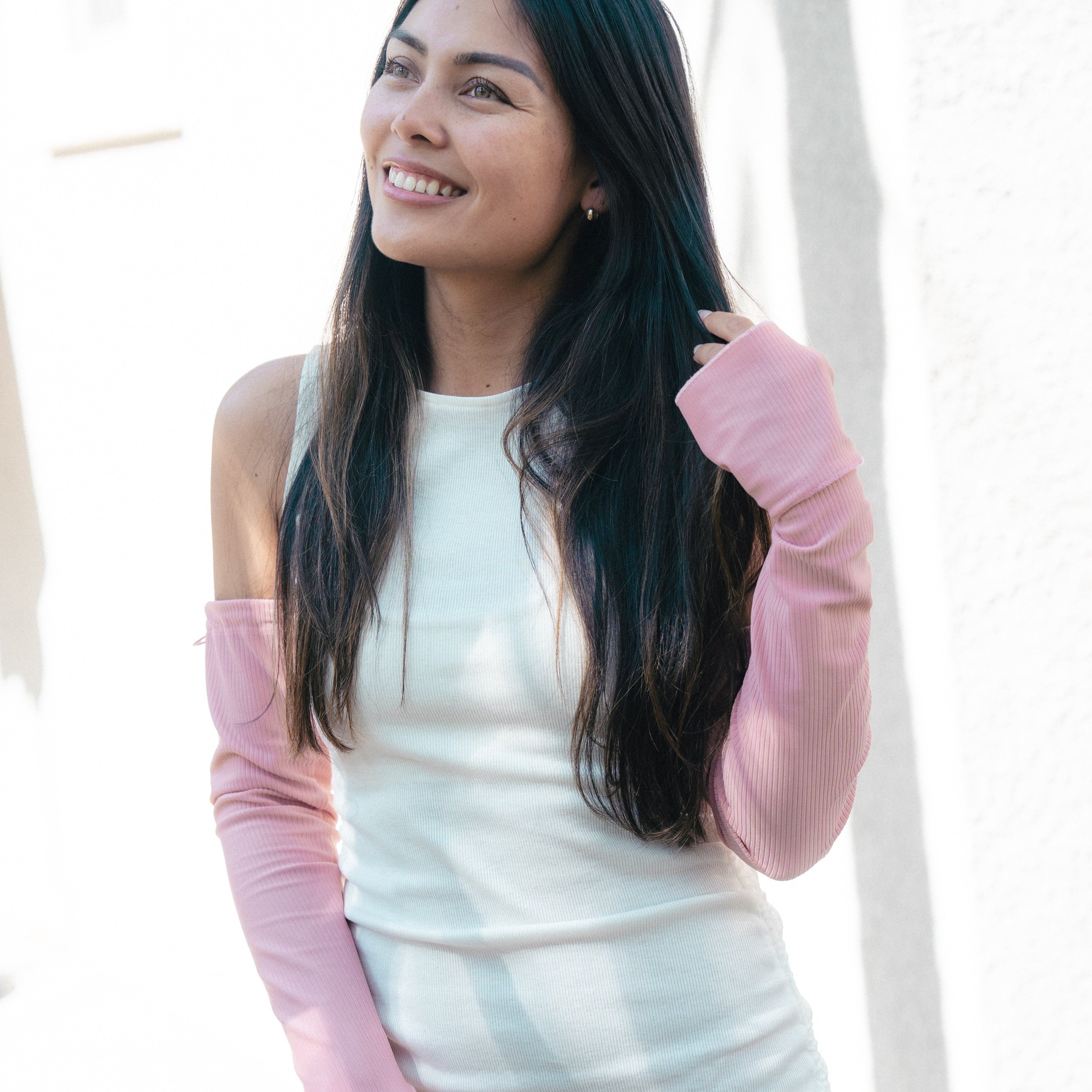 Woman wearing a white dress with pink sleeves against a white background