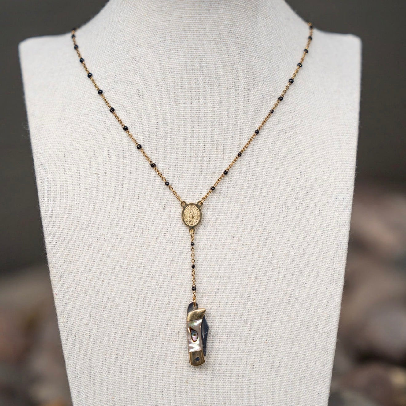 Necklace with pendant on a mannequin bust against a natural stone background