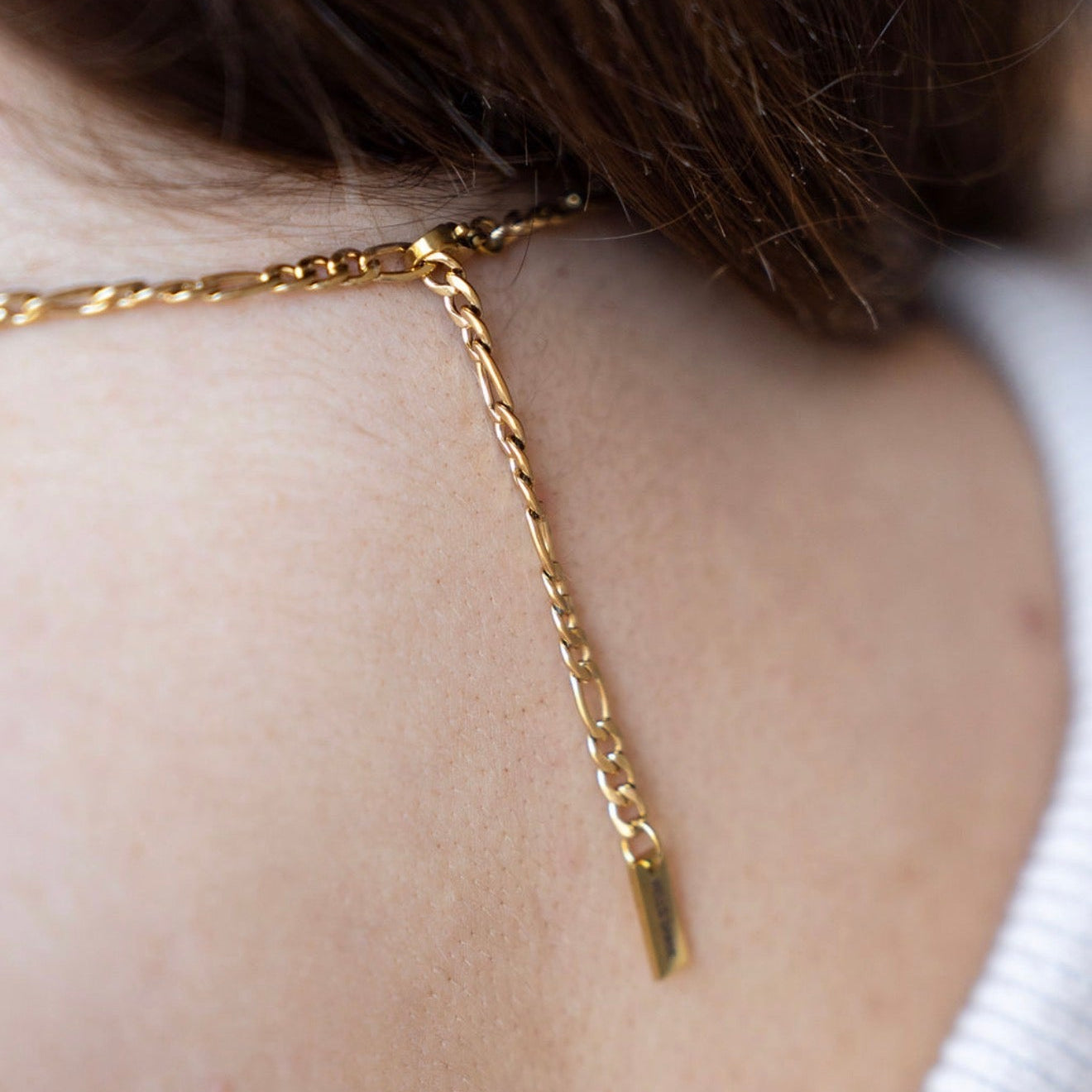 Gold chain necklace on a person's neck with a blurred background