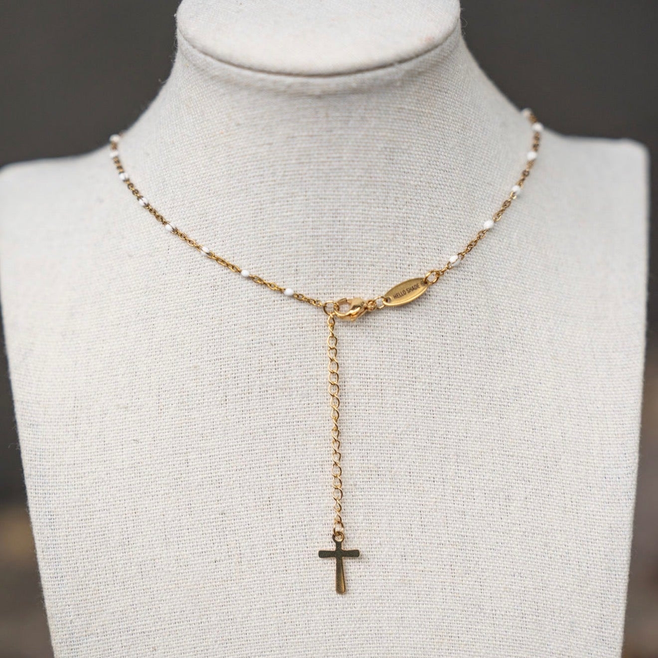 Gold necklace with a cross pendant on a mannequin bust.