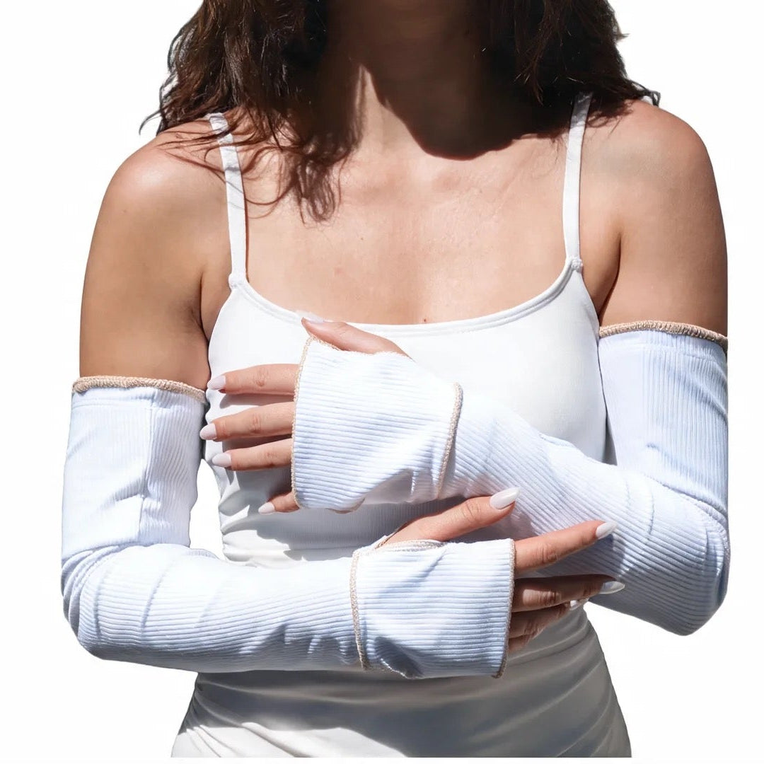 Woman wearing a white tank top and white arm sleeves on a white background