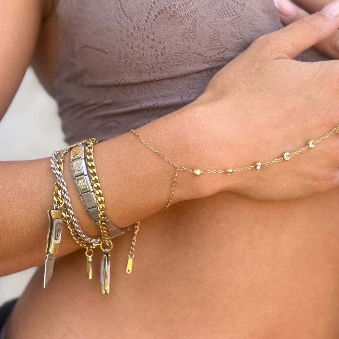 Close-up of a person wearing multiple gold bracelets on their wrist.