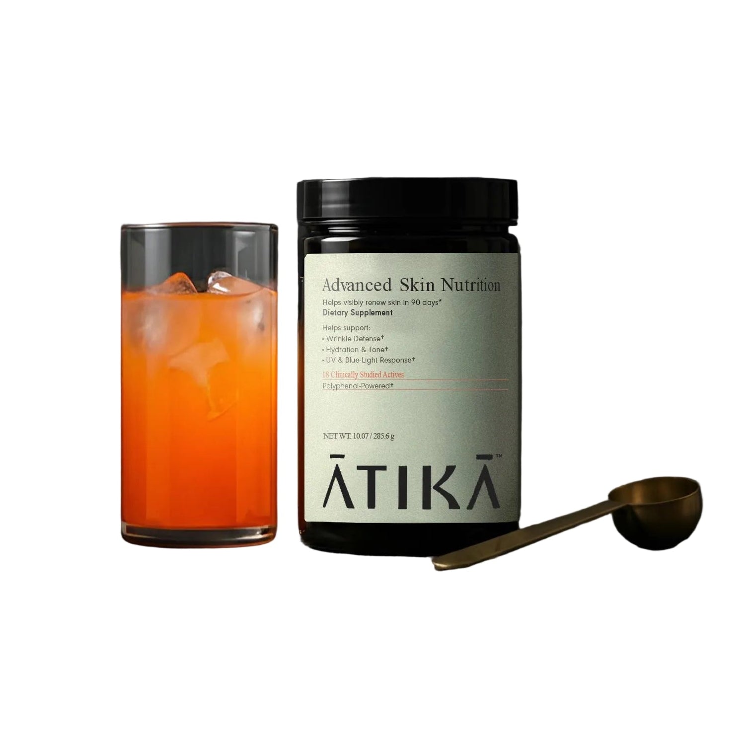 Jar of 'ĀTIKA Advanced Skin Nutrition' on a dark surface with an orange beverage in the foreground.