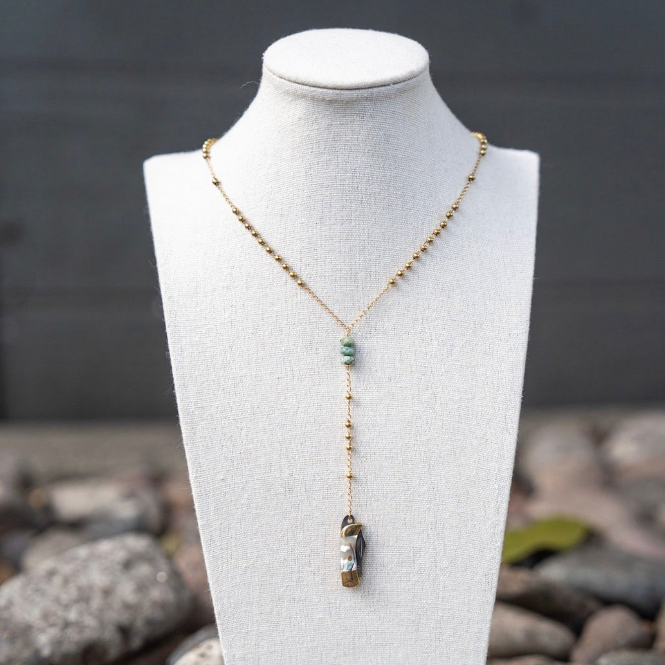 Necklace with a pendant on a mannequin bust against a natural stone background