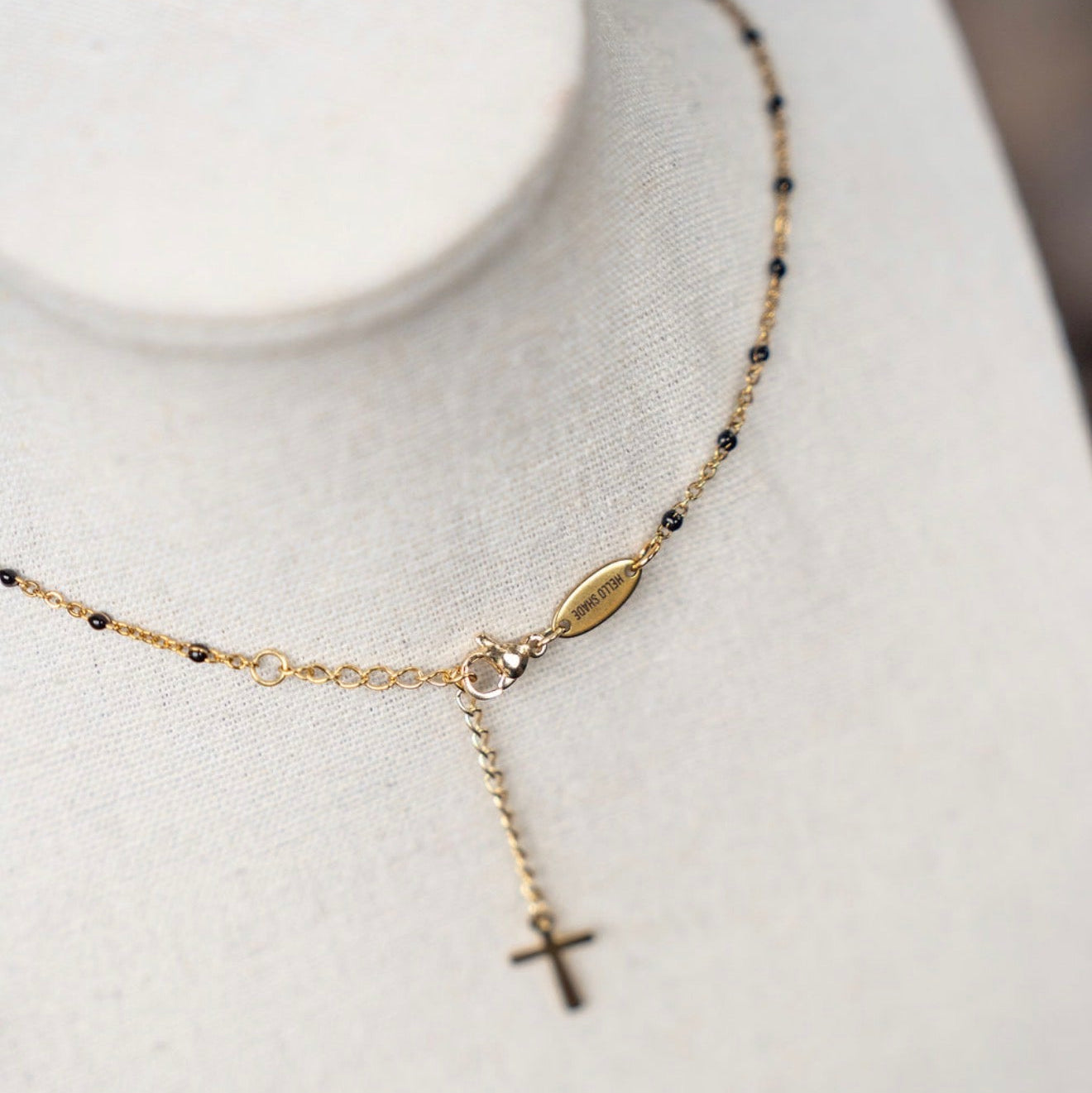 Gold necklace with a cross pendant on a white mannequin bust.