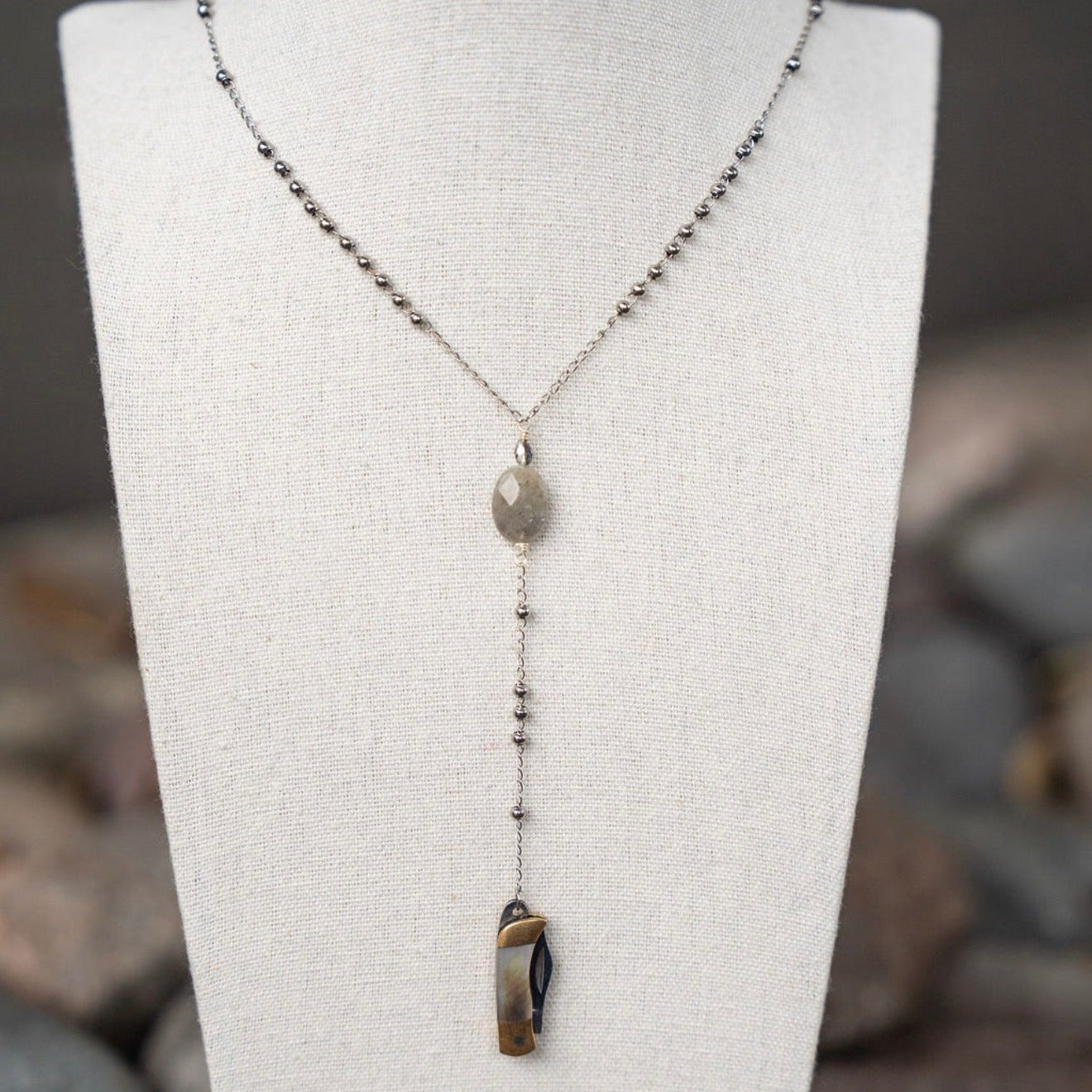 Necklace with a pendant on a mannequin bust against a natural stone background