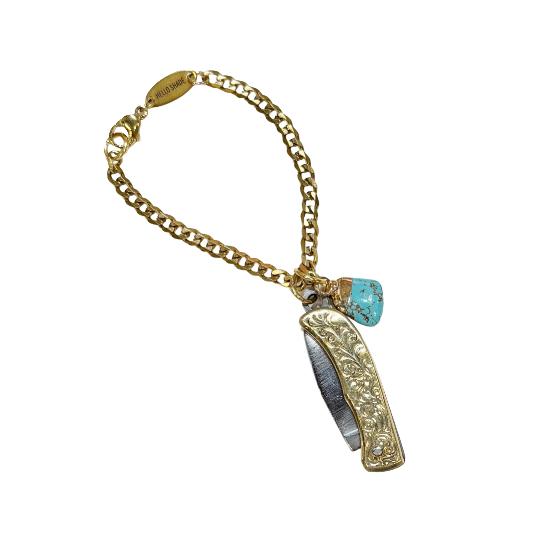 Gold chain bracelet with a decorative pendant and turquoise stone on a white background