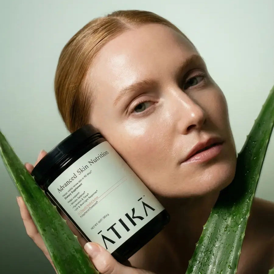 Woman holding a jar of Atika Advanced Skin Nutrition with aloe vera leaves in the foreground
